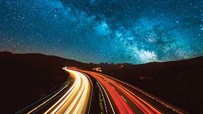 smugi świetlne samochodów na drodze pod rozgwieżdżonym niebem w nocy