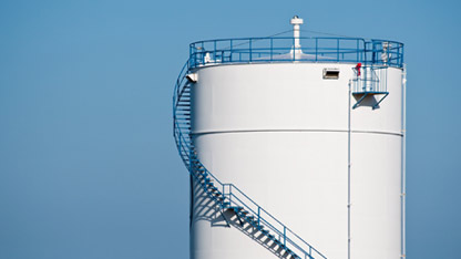 Biały zbiornik naftowy na tle bezchmurnego niebieskiego nieba