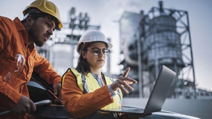 Zespół inżynierów terenowych pracujących nad przeglądaniem raportów na laptopie.