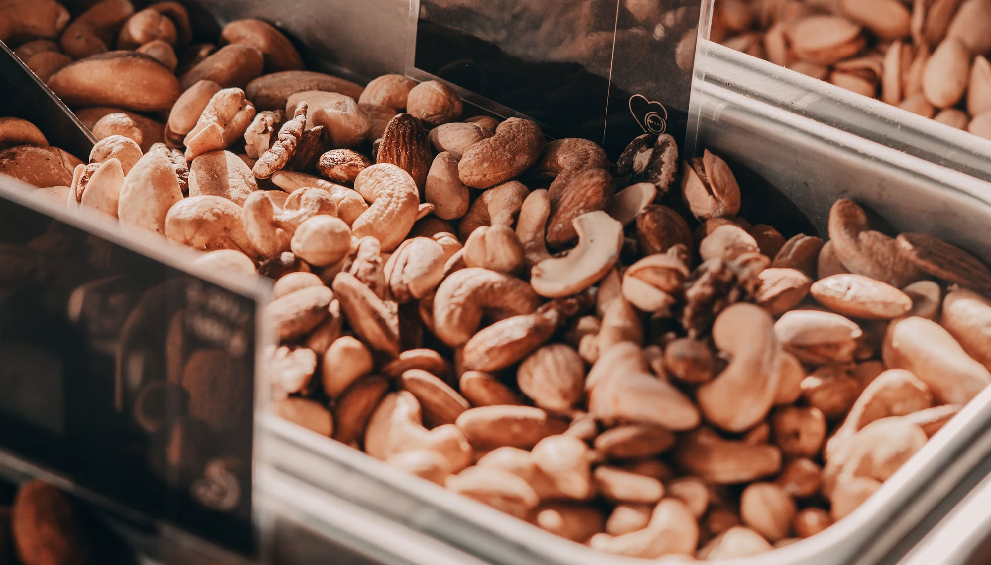 Zblizenie na mieszankę orzechów, w tym nerkowce, migdały i orzechy włoskie, wyłożone w metalowym pojemniku.