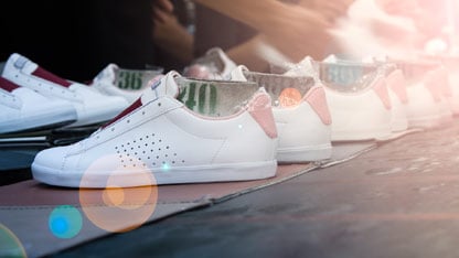 Linia białych butów sportowych na taśmie produkcyjnej w fabryce obuwia.